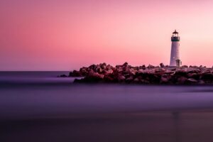 Lighthouse silhouette against a dusk sky over the water