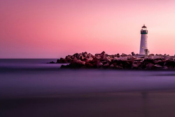 Lighthouse silhouette against a dusk sky over the water