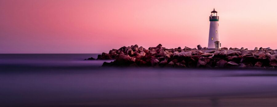 Lighthouse silhouette against a dusk sky over the water